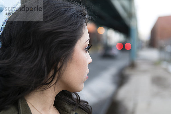 Profilporträt einer jungen Frau in der Stadt  die ihr über die Schulter schaut