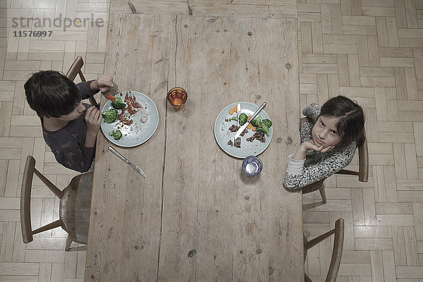 Porträt eines Mädchens und eines Bruders beim Abendessen am Küchentisch