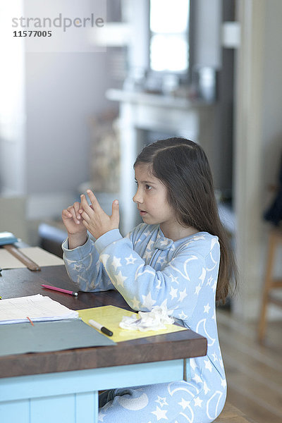 Mädchen macht Hausaufgaben und zählt am Küchentisch an den Fingern