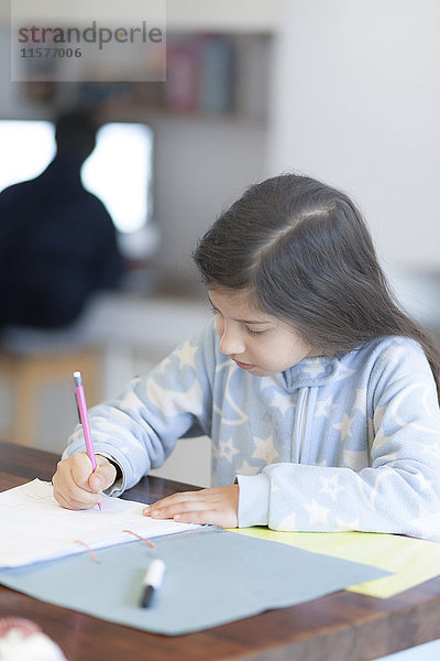 Mädchen macht Hausaufgaben am Küchentisch