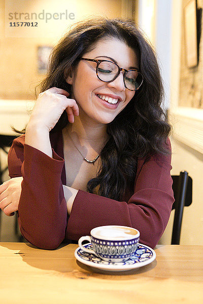 Porträt einer jungen Frau mit geschlossenen Augen am Kaffeetisch