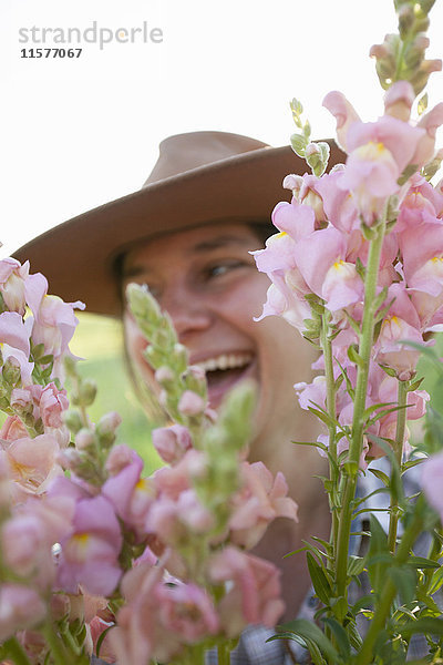 Nahaufnahme einer jungen Frau  die einen Strauss Löwenmäulchen (Antirrhinum) von einem Feld einer Blumenfarm hält