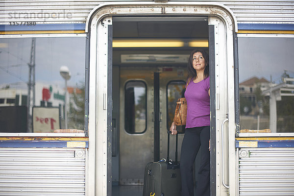 Eine reife Frau schaut auf dem Bahnsteig aus der Zugtür