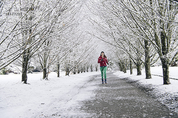 Frau joggt entlang eines Weges  in schneebedeckter ländlicher Umgebung
