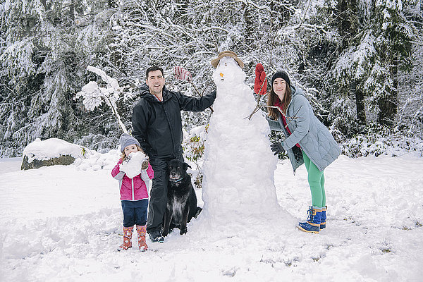 Porträt einer jungen Familie  die einen Schneemann baut