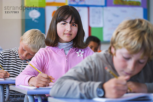 Porträt eines Mädchens im Klassenzimmer  am Schreibtisch sitzend  bei der Klassenarbeit