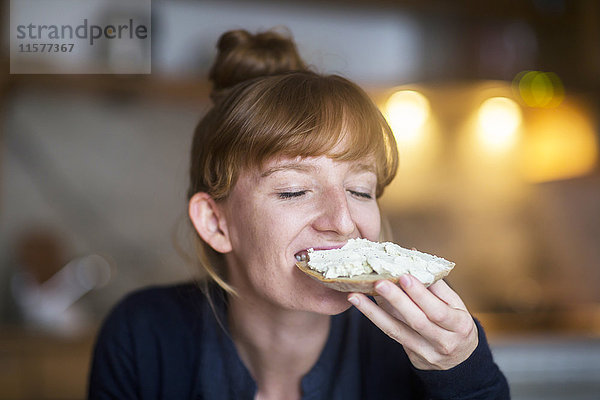 Junge Frau isst Brot mit Frischkäse
