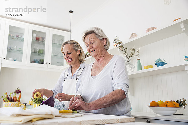 Ältere Frau und Tochter bereiten Gemüse am Küchentisch zu
