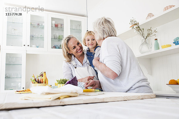Ältere Frau  Tochter und Enkelin bereiten Gemüse am Küchentisch zu