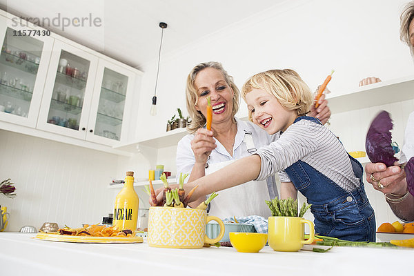 Mädchen und Mutter bereiten Karotten am Küchentisch zu