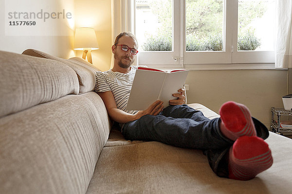 Mann entspannt sich auf dem Sofa  liest Buch