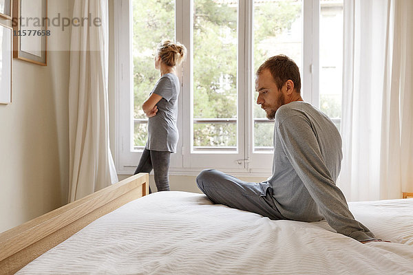 Mittelgroßes erwachsenes Paar im Schlafzimmer  das Meinungsverschiedenheiten hat