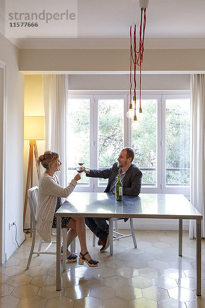 Mittleres erwachsenes Paar  das sich zu Hause entspannt  ein Glas Wein trinkt und einen Toast ausbringt