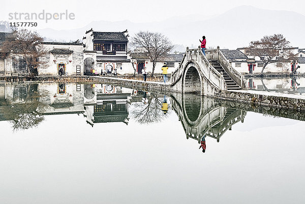 Spiegelbild von traditionellen Häusern und Fußgängerbrücke über den See  Hongcun Village  Provinz Anhui  China