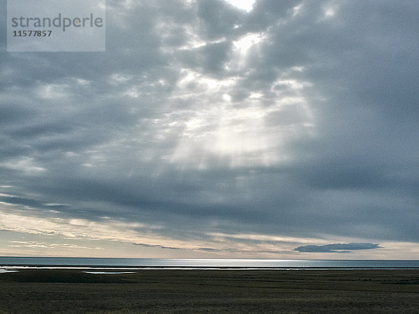 Sonnenstrahlen vom grauen Wolkenhimmel über dem Meereshorizont  Reykjavik  Island