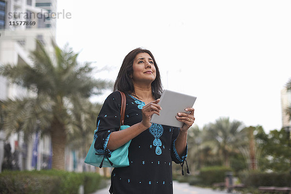 Ältere Geschäftsfrau mit digitalem Tablet in der Stadt  Dubai  Vereinigte Arabische Emirate