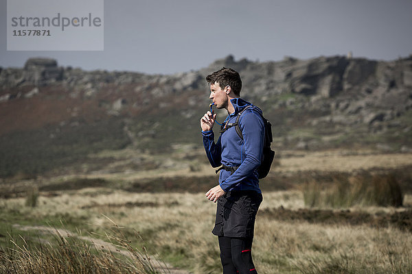 Männlicher Läufer trinkt aus der Tube in Stanage Edge  Peak District  Derbyshire  UK