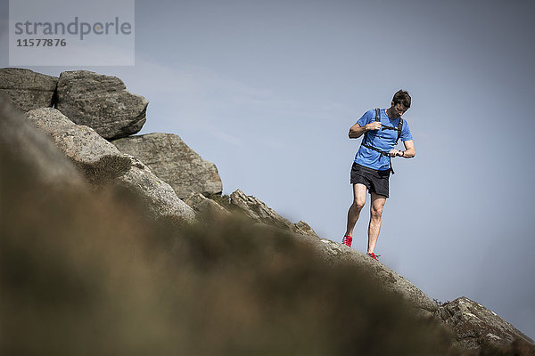Männlicher Läufer schaut auf Smartwatch am Stanage Edge  Peak District  Derbyshire  UK