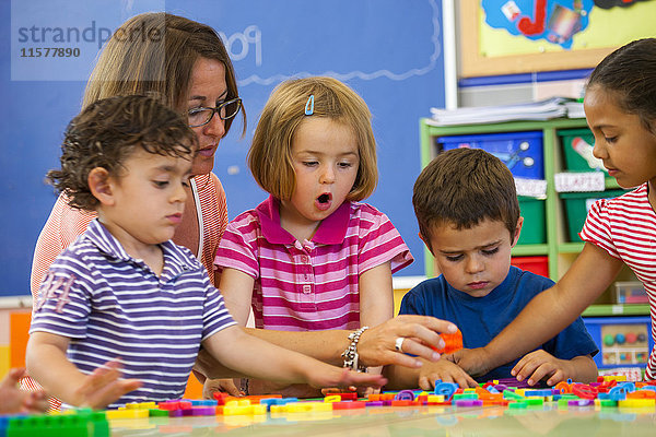 Weibliche Lehrerin mit Jungen und Mädchen im Vorschulalter  die im Klassenzimmer das Alphabet lernen