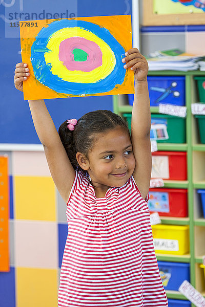 Vorschulmädchen hält buntes Kreisbild im Klassenzimmer