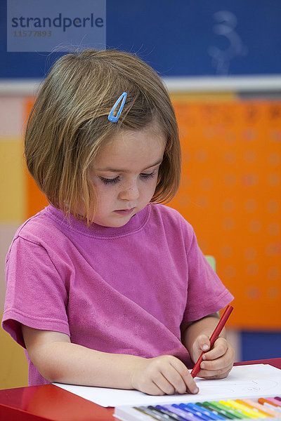 Vorschulmädchen mit Malstift im Klassenzimmer