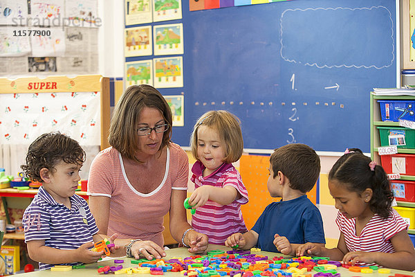 Weibliche Lehrerin mit Jungen und Mädchen im Vorschulalter  die im Klassenzimmer das Alphabet lernen