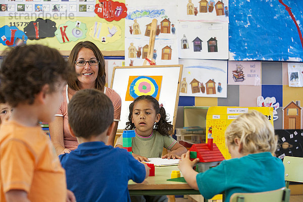 Jungen und Mädchen im Vorschulalter bauen mit Spielzeugbausteinen im Klassenzimmer