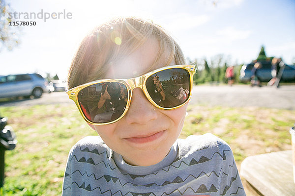 Porträt des süßen Jungen in goldener Sonnenbrille im Park