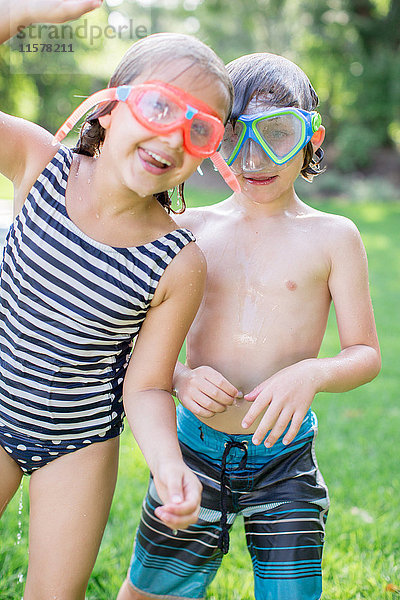 Porträt eines Jungen und eines Mädchens im Garten mit Schwimmbrille