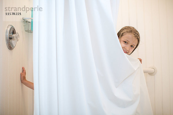 Porträt eines Mädchens  das aus einem Duschvorhang schaut