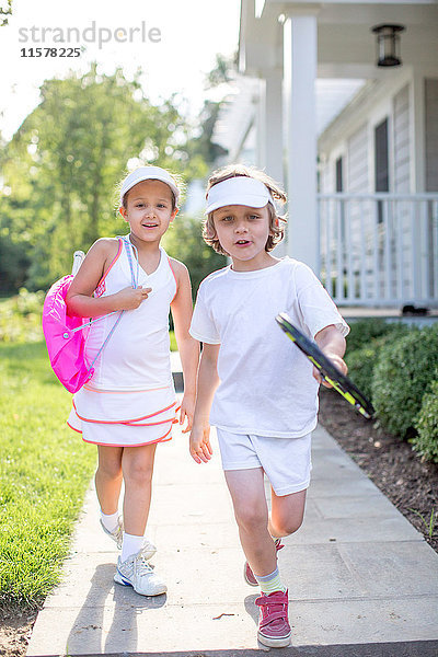 Porträt eines Tennisspielers (Junge und Mädchen) auf einem Gartenweg