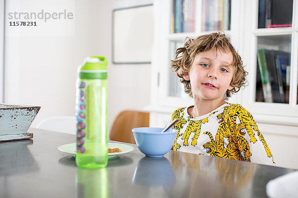 Porträt eines Jungen beim Frühstück am Küchentisch