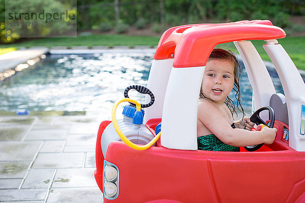 Mädchen fährt Spielzeugauto am Freibad