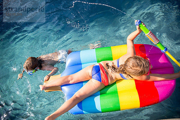 Draufsicht auf einen schwimmenden Jungen und ein aufblasbares Mädchen im Freibad