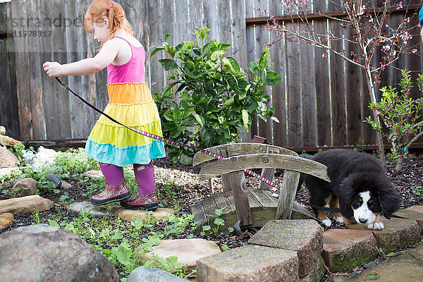 Junges Mädchen versucht  mit Hund im Garten Gassi zu gehen