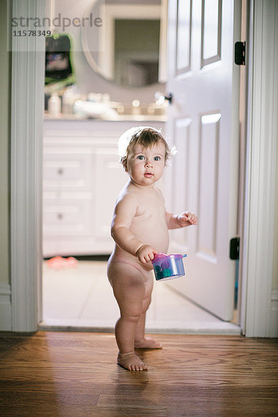 Porträt eines nackten weiblichen Kleinkindes im Türrahmen stehend