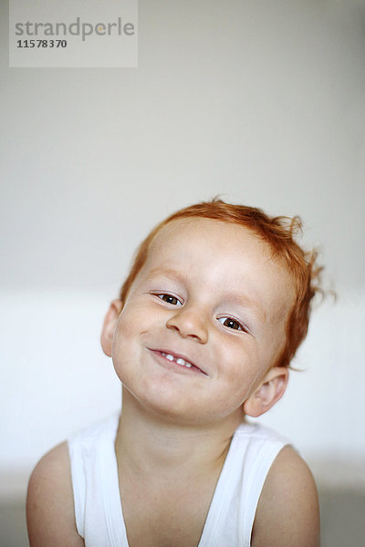 Porträt eines rothaarigen kleinen Jungen mit lächelndem Tank Top  drinnen