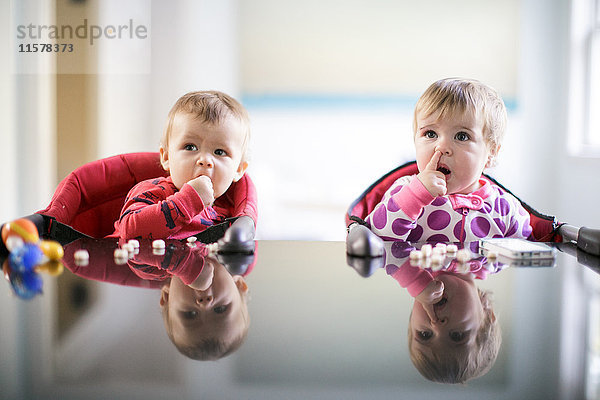 Männliche und weibliche Kleinkinder an der Küchentheke  die in der Nase bohren und Süßigkeiten essen