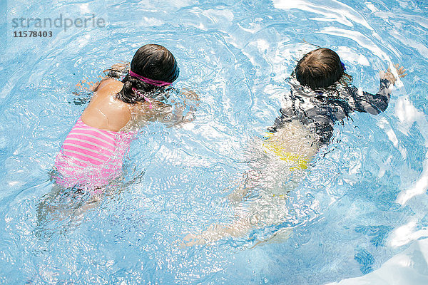 Draufsicht auf einen Jungen und ein Mädchen  die im Freibad schwimmen