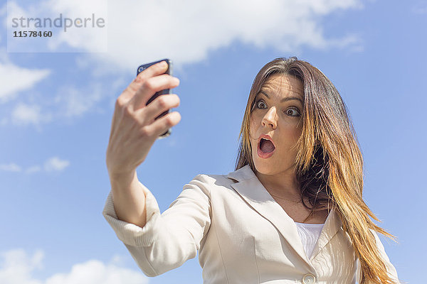 Hübsche brünette Frau beim Selfie mit Smartphone