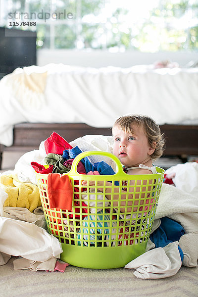 Weibliches Kleinkind sitzt im Korb zwischen der Wäsche