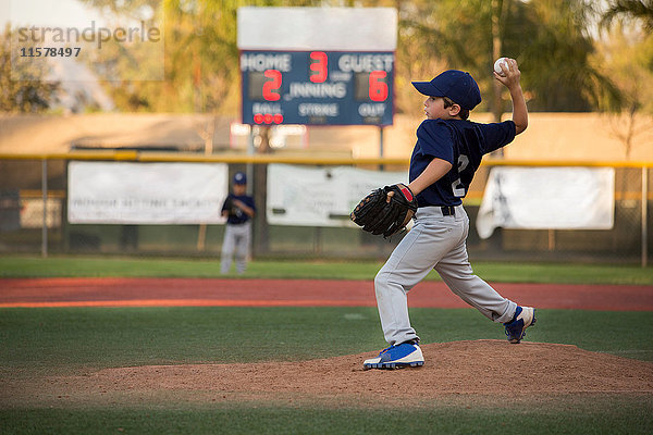 Jungen-Baseball-Werfer  der den Ball auf das Baseballfeld wirft