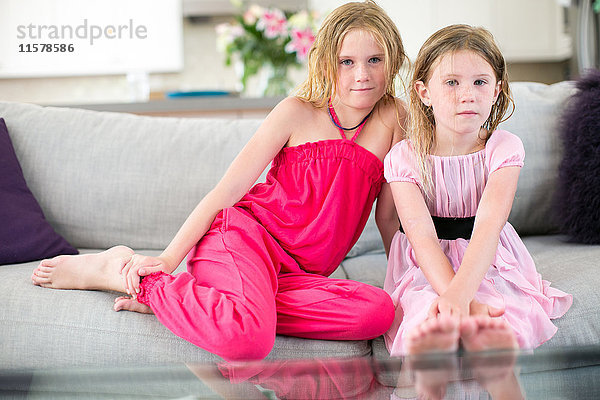 Porträt von zwei jungen Schwestern auf dem Sofa sitzend
