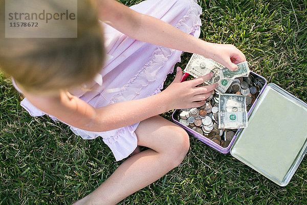 Draufsicht eines Mädchens  das Dollarnoten auf Gras zählt