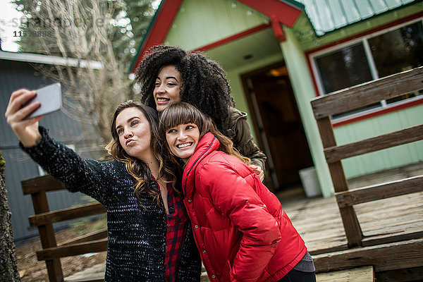 Drei Freunde stehen neben der Kabine  nehmen Selfie  benutzen das Smartphone.