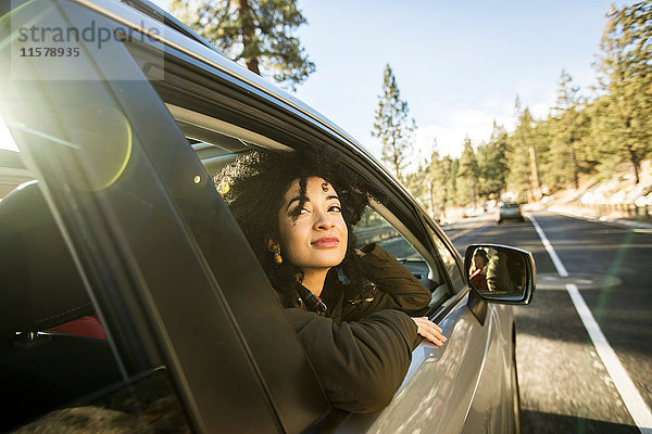 Junge Frau schaut aus dem Fenster eines fahrenden Autos
