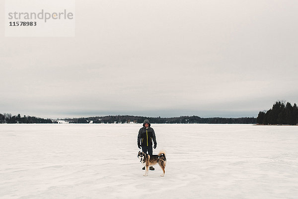 Porträt eines Mannes mit Schlittenhund in schneebedeckter Landschaft