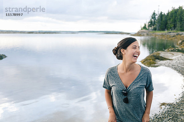 Junge Frau lacht am Kiesstrand  Maine  USA