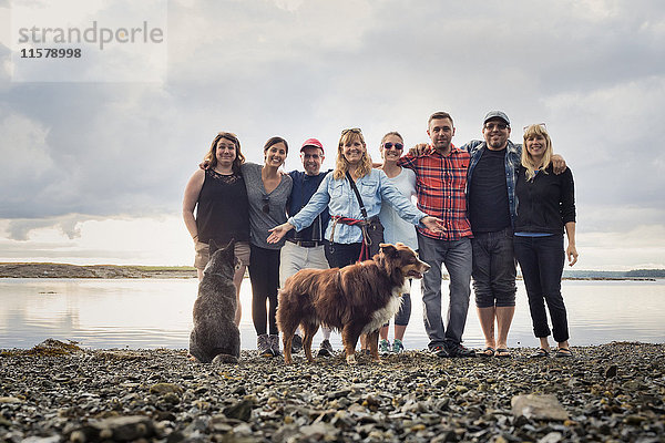 Porträt einer erwachsenen Familie und Hunden am Kiesstrand  Maine  USA