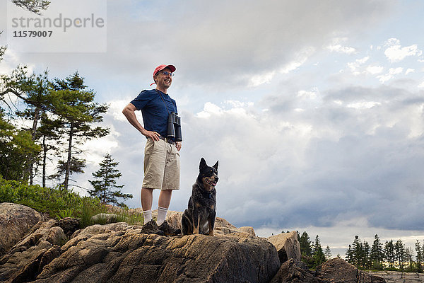 Älterer Mann und Hund schauen auf die Küste von Maine  USA